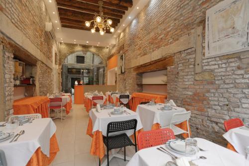 a restaurant with white tables and chairs and a brick wall at Al Mascaron Ridente in Venice