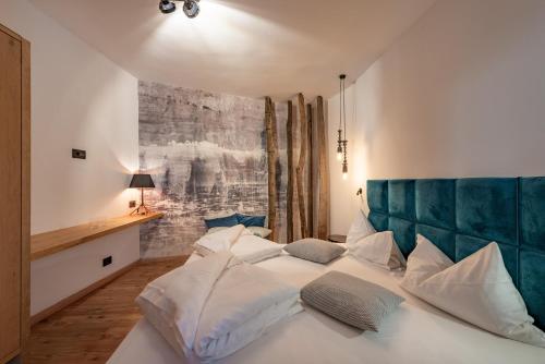 a bedroom with a white bed with a green headboard at Hotel Goldene Traube in Termeno