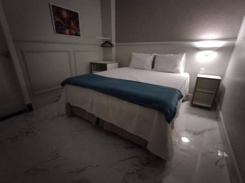 a bedroom with a large bed with a blue blanket at Antonio's Hotel e Spa - Airport in Brasilia