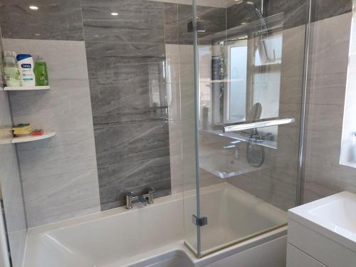 a bathroom with a shower with a tub and a sink at Home accommodation in Southampton