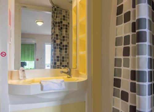 ein Bad mit einem Waschbecken und einem Spiegel in der Unterkunft Fasthotel Orléans Nord Artenay in Artenay