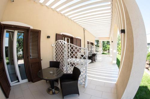 a patio with a white pergola and a table and chairs at Isola Verde Agriturismo in Carovigno