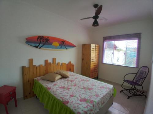 a bedroom with a bed and a surfboard on the wall at Casa com Jardim na Praia de Guaratiba, Maricá in Maricá