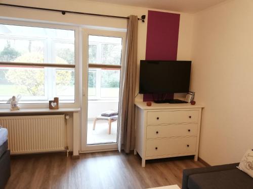 een slaapkamer met een televisie op een dressoir met een raam bij Sahlenburger Ferienhaus in Cuxhaven