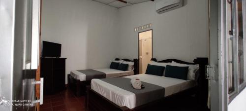 a bedroom with two beds and a television at Hotel Villa Ángel in Neiva
