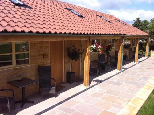 ein Haus mit einem roten Dach und einer Terrasse in der Unterkunft The Cholmeley Arms in Burton Coggles