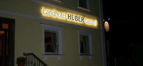 a sign on the side of a building with a clock at Landhotel Gasthof Huber in Merching
