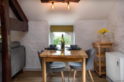 a dining room with a wooden table and a bottle of wine at The Granary in Bryn-crug