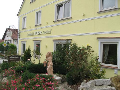 a yellow building with a bear statue in front of it at Landhotel Gasthof Huber in Merching