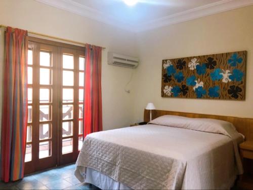 1 dormitorio con 1 cama y puerta corredera de cristal en Suite 1201 IlhaFlat Frente ao Mar, en Ilhabela