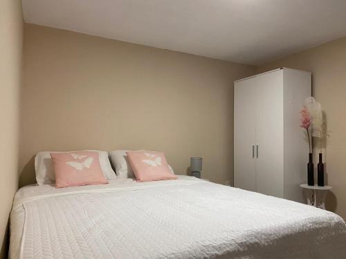 a bedroom with a bed with pink pillows and a cabinet at Place2cu-Studio apartment in Willemstad