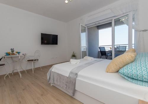 a white bedroom with a large bed and a table at Seaview apartments Oscar in Makarska