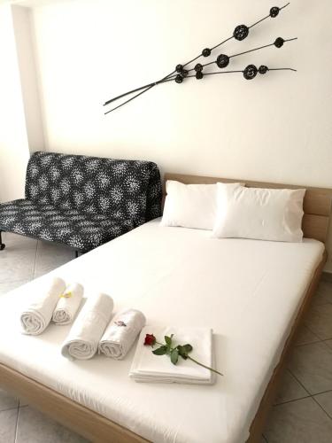 a white bed with two towels and a clock on the wall at Iliana's house in Naousa