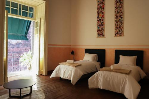 a room with two beds and a table and a window at Viajero CDMX Centro Hostel in Mexico City