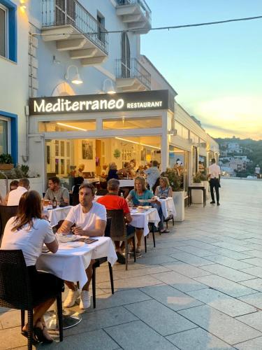 a group of people sitting at tables outside a restaurant at Smart Suite & Apartments in Santa Teresa Gallura