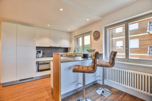 a kitchen with white cabinets and a counter with two stools at Valaisia 125 in Riederalp
