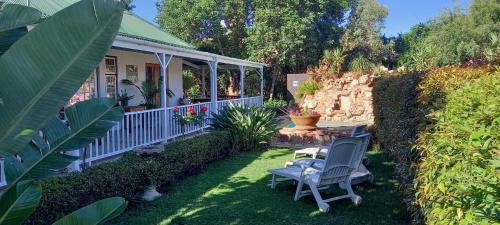 a house with two chairs and a table in the yard at Best Little Guesthouse -Beit Shalom in Oudtshoorn