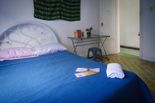 Un dormitorio con una cama azul con una manta azul y una mesa en Hostal Azul Puebla Barrio El Alto en Puebla
