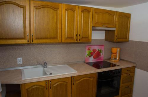 a kitchen with wooden cabinets and a white sink at Kuca za odmor Poppke in FeriÄanci