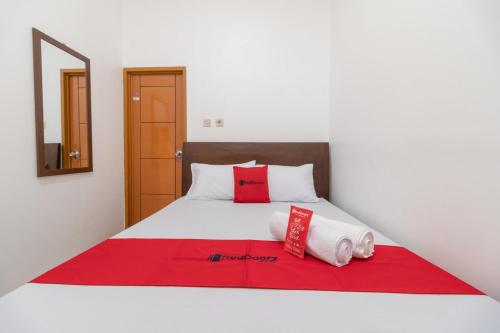 Un dormitorio con una cama con almohadas rojas. en RedDoorz Syariah near Summarecon Mall Bekasi en Kayuringin