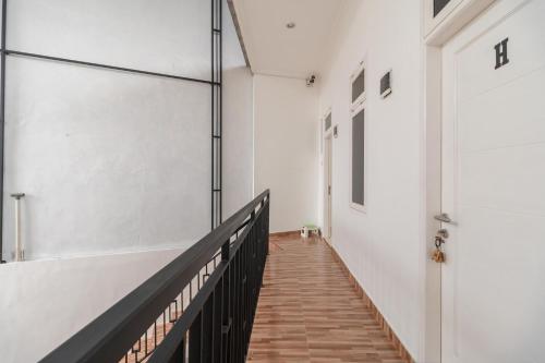 a hallway with white walls and wooden stairs at RedDoorz Syariah near Summarecon Mall Bekasi in Kayuringin