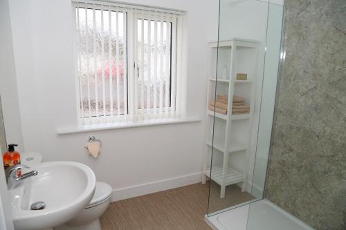 een badkamer met een wastafel, een toilet en een raam bij Kelton Croft in Kirkland