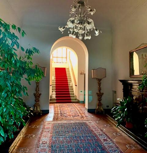 a hallway with a chandelier and a red staircase at Villa Il Padule in Bagno a Ripoli