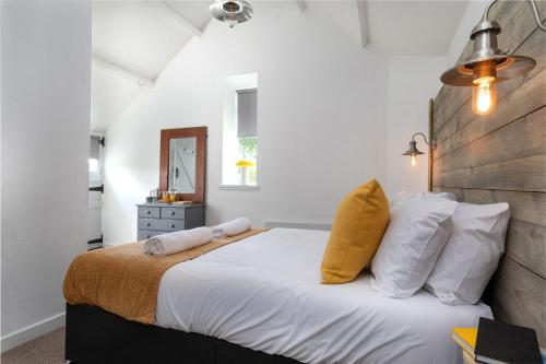 Schlafzimmer mit einem Bett mit weißer Bettwäsche und gelben Kissen in der Unterkunft The Cowshed in Bryn-crug