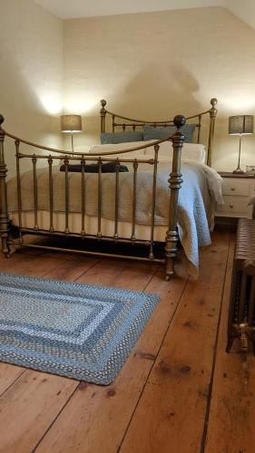 a bedroom with a bed and a rug on a wooden floor at The Hideaway in Falmouth