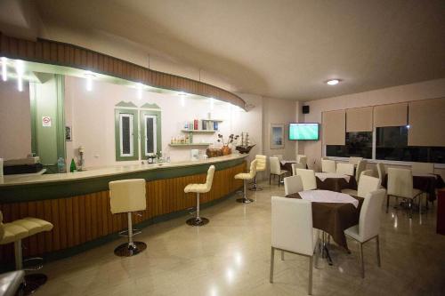 un restaurante con un bar con mesas y sillas blancas en Remvi Hotel - Apartments en Stoúpa