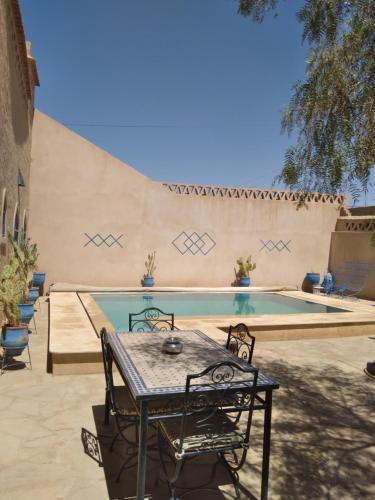 a table and chairs next to a swimming pool at Maison Mirage B&B in Hassilabied