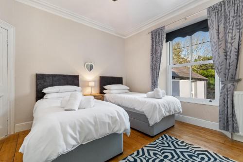 two beds in a bedroom with a window at Cartref - Beautiful Cottage, Hot Tub, Countryside Views in Saundersfoot