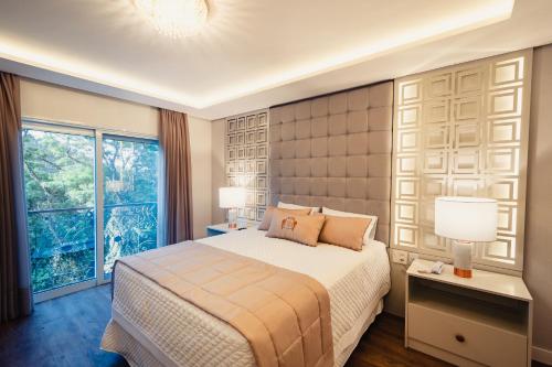 a bedroom with a bed and a large window at HOTEL RF VISION restaurante giratório in Gramado