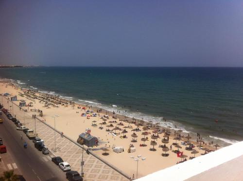 a beach with a lot of umbrellas and the ocean at Residence Boujaafar in Sousse
