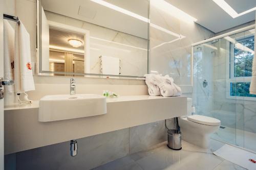 a bathroom with a sink and a toilet and a mirror at Hotel e Restaurante GIRATÓRIO RF Vision - A melhor vista 360 de Gramado in Gramado