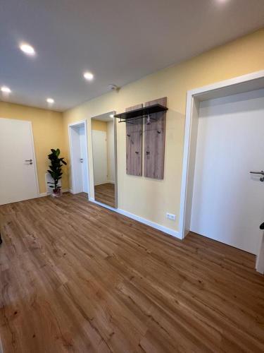 an empty room with wood floors and a room with a door at Ferienhaus LEMA in Schopfloch