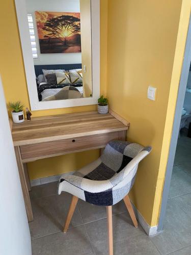 a vanity with a mirror and a chair in a room at Résidence La Baie 1 Océane in La Trinité