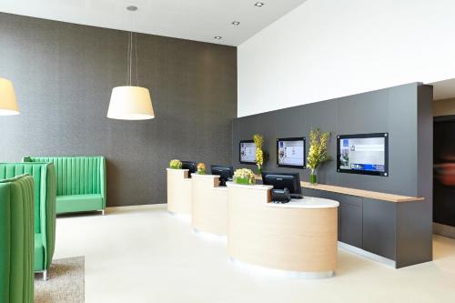 a waiting room with green chairs and reception desks at Novotel London Wembley in London