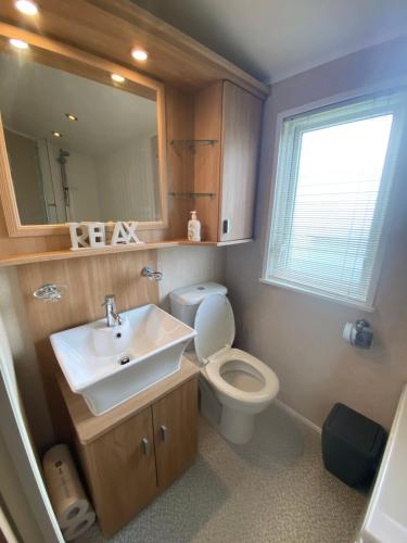 a bathroom with a sink and a toilet and a mirror at Cosy & Modern Cabin In Heart of Northumberland in Swarland