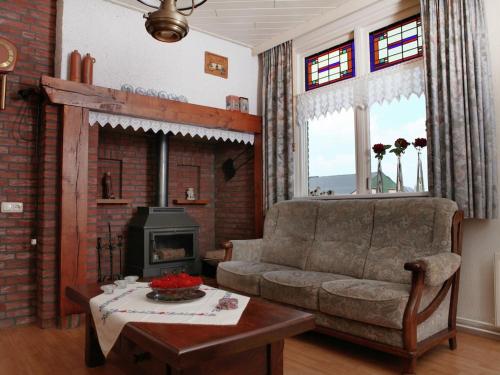 een woonkamer met een bank en een open haard bij Tranquil Farmhouse near Forest in Ulicoten with Terrace in Ulicoten