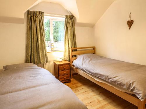 two beds in a bedroom with a window at Cloud View Cottage in Ashbourne