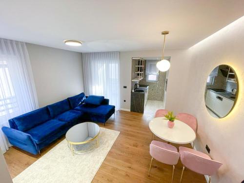 uma sala de estar com um sofá azul e uma mesa em Premium Apartmani Banja Luka em Banja Luka