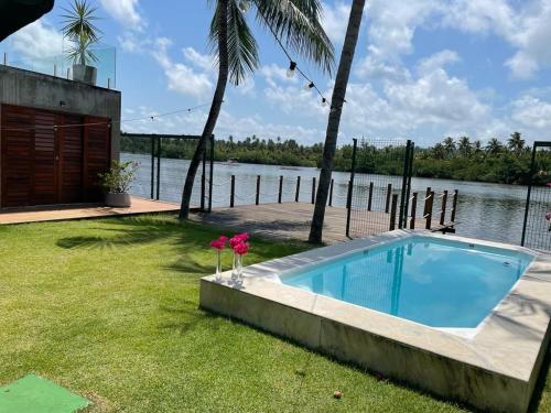 a swimming pool in a yard next to a body of water at Casa da Massagueira-AL in Marechal Deodoro