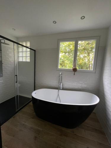 a large bath tub in a bathroom with a window at Les jardins de l'Hermitage in Cellettes
