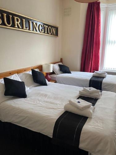 a room with three beds with towels on them at Burlington Hotel in Sandown