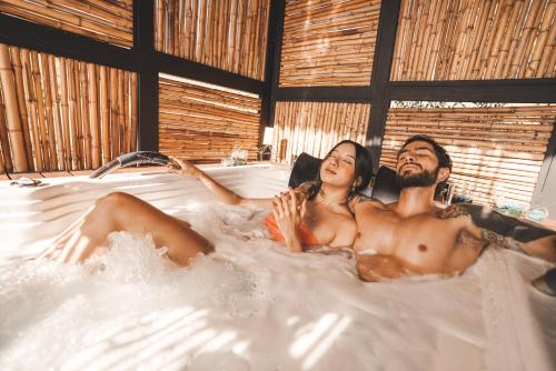 a man and woman laying in a bath tub at Cardinal Glamping in Guatapé