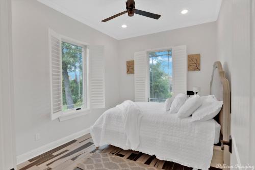 - une chambre blanche avec un lit et un ventilateur de plafond dans l'établissement The Cross Lake Maison, à Shreveport