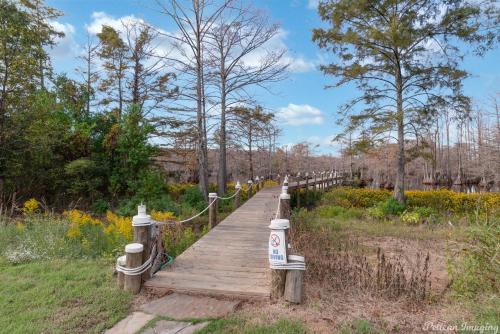 a wooden boardwalk in a field with trees and flowers at The Cross Lake Maison in Shreveport