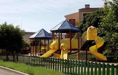 a playground with two slides in front of a fence at Albir Garden Resort in Albir