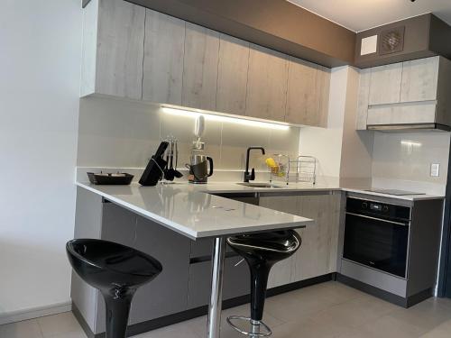 uma cozinha com um balcão e dois bancos pretos em Edificio Curitiba, Apartamento nuevo y céntrico 1B 1D em Temuco